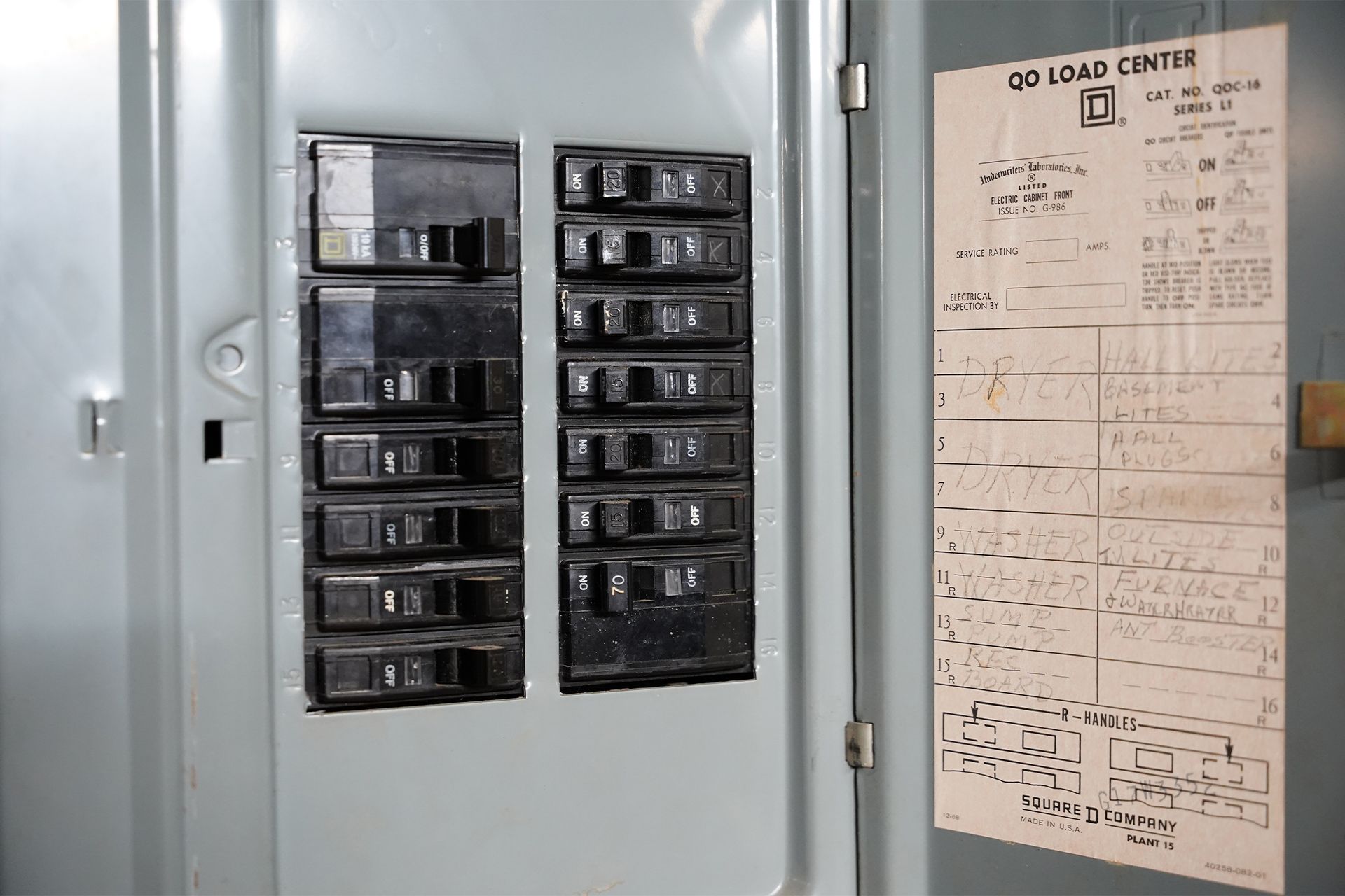 Gray electrical breaker panel with multiple switches, and a label on the door.