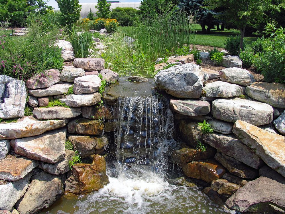 A lush green garden with waterfall cascading down the rocky stones