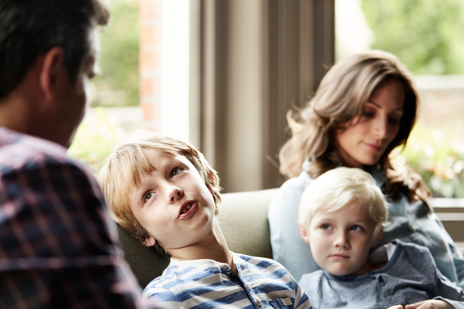 Famiglia di quattro persone, due genitori e due figli piccoli, seduti all'interno, che conversano.