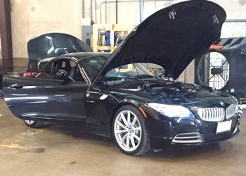 A black bmw with its hood open in a garage