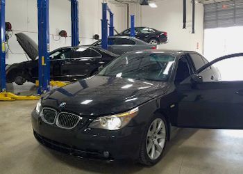 A black bmw is parked in a garage with its doors open.