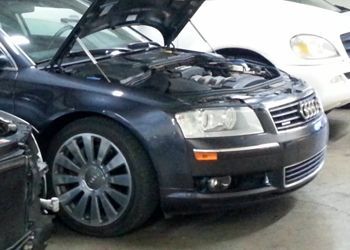 A black audi with the hood up is parked in a garage