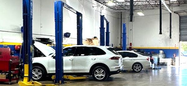 A white car is sitting on a lift in a garage.