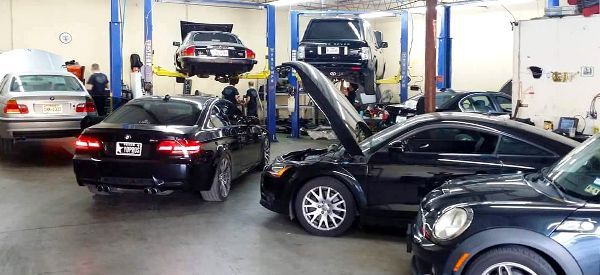 A group of cars are sitting in a garage with their hoods open.