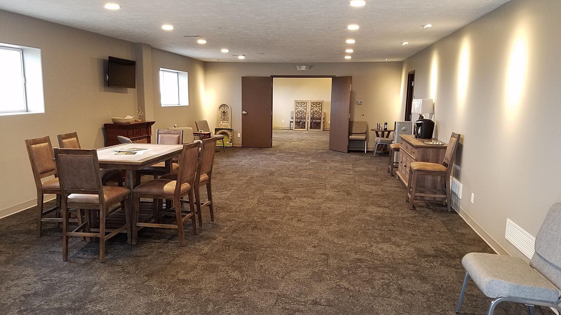 Room with table and chairs, tan walls, carpet, and a doorway to another room.