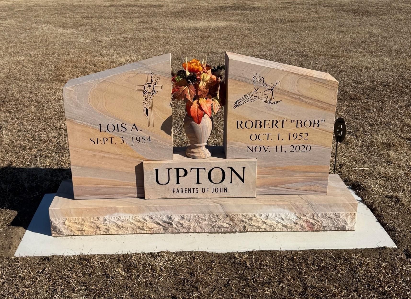 Grave with split headstones, flower arrangement, and 