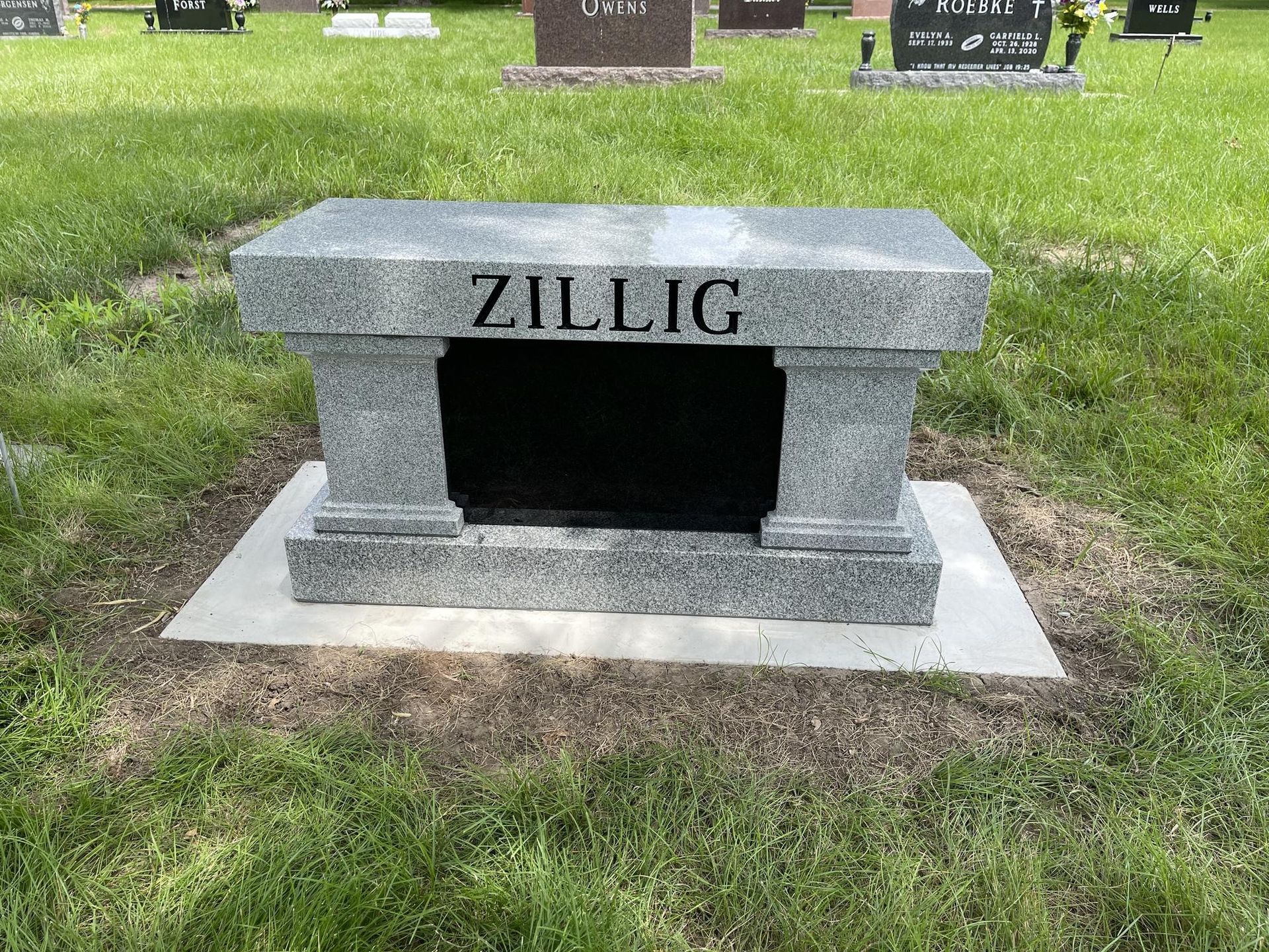 Gray granite bench-style headstone engraved with the surname 