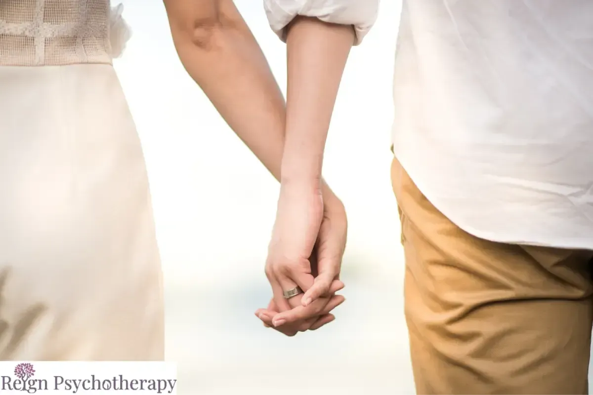 A close-up shot of a couple walking together and holding hands.