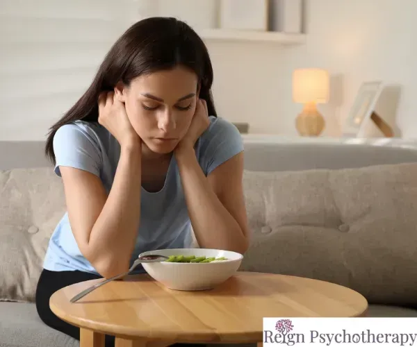 A therapy office setting featuring two comfortable armchairs facing each other near a large window.