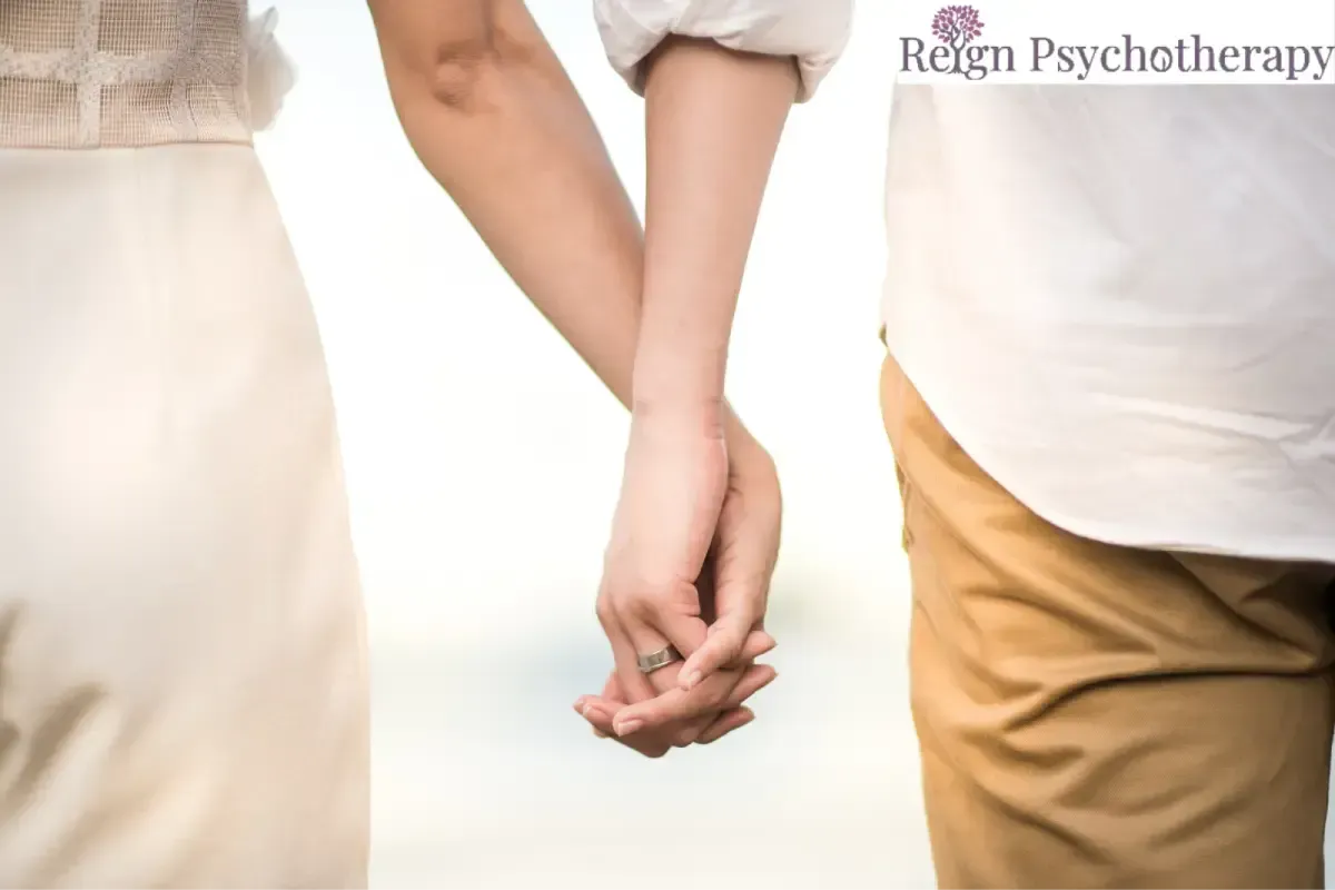 A close-up shot of a couple walking together and holding hands.