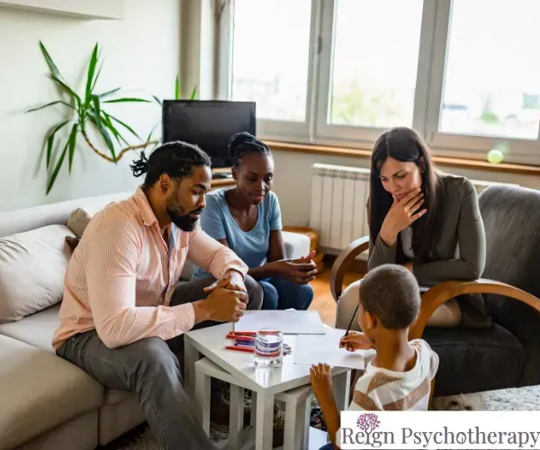 A mental health professional and a client sit in comfortable armchairs in a bright, modern office during a one-on-one session.