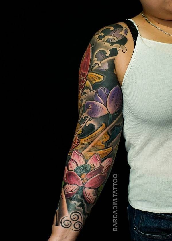A woman has a full sleeve tattoo of flowers on her arm.