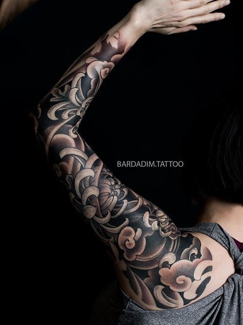 A woman has a full sleeve tattoo on her arm.