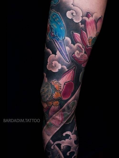A tattoo of a bird and flowers on a person 's leg.