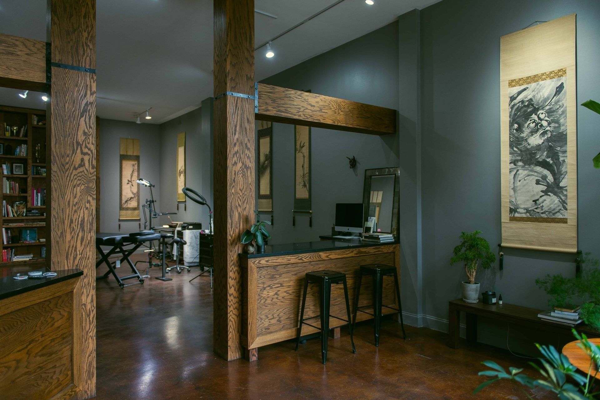 A large room with a bar and stools and a painting on the wall.