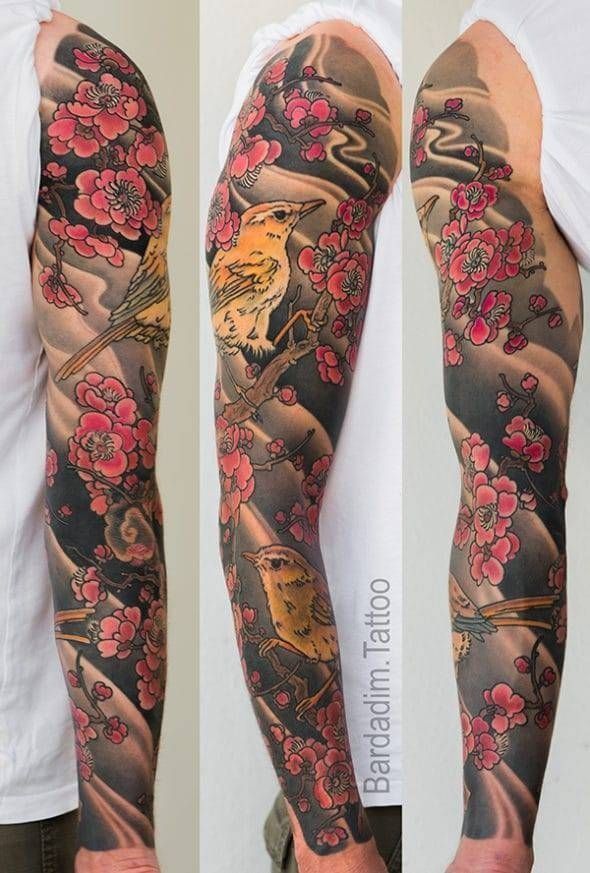 A man has a full sleeve tattoo of flowers and birds
