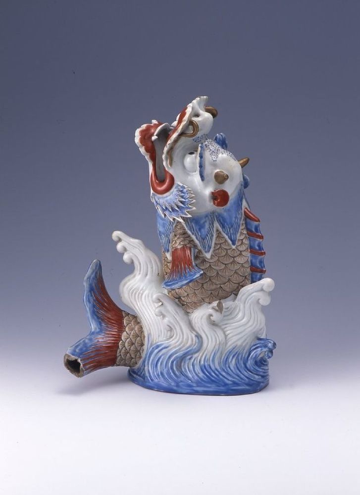 A statue of a dragon swimming in the ocean on a white surface.