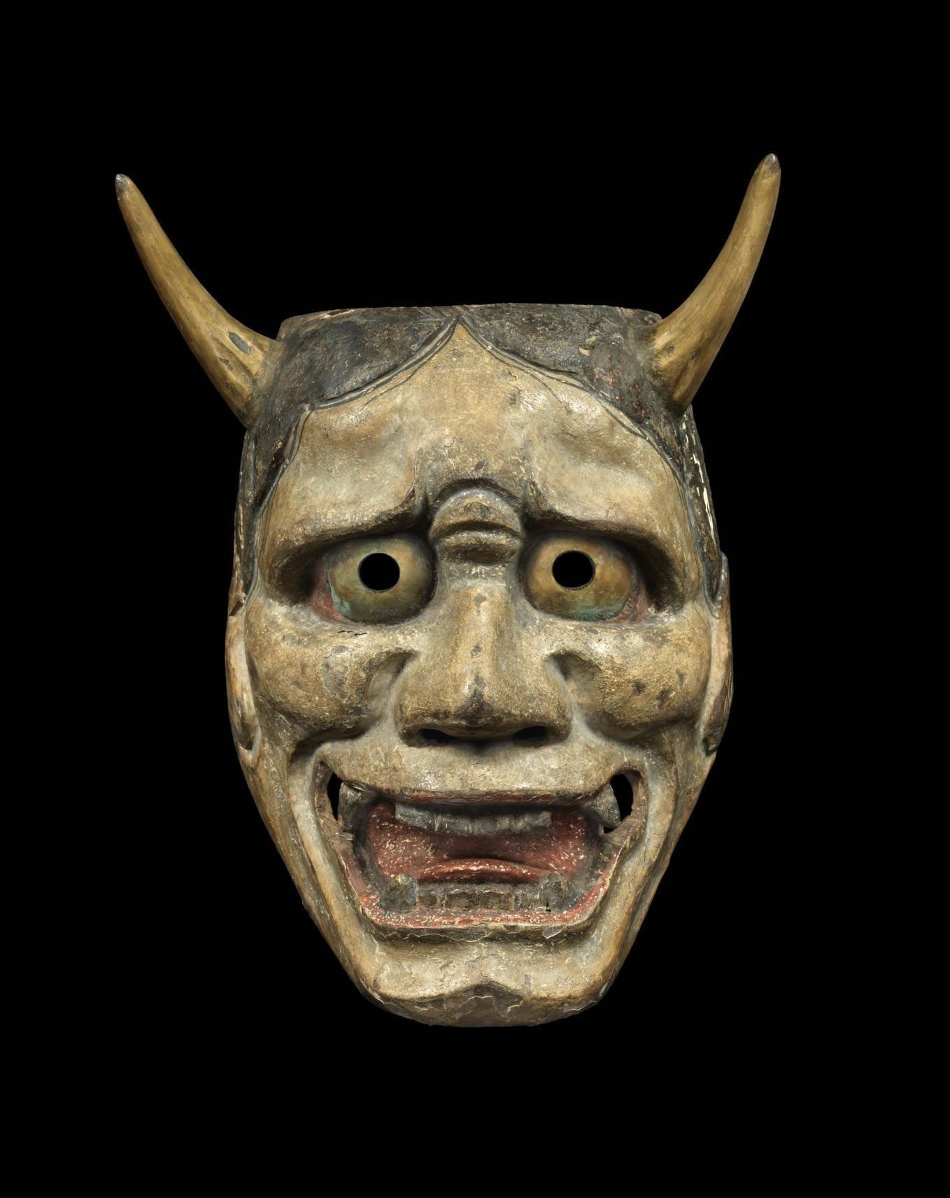 A close up of a demon mask with horns on a black background.