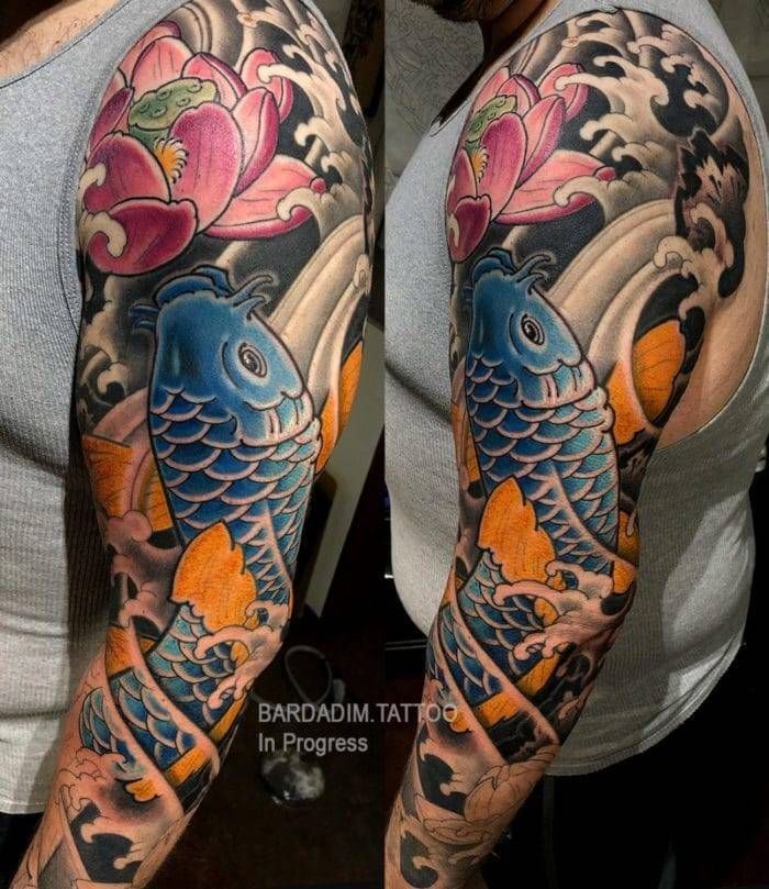 A man has a full sleeve tattoo of a fish and flowers