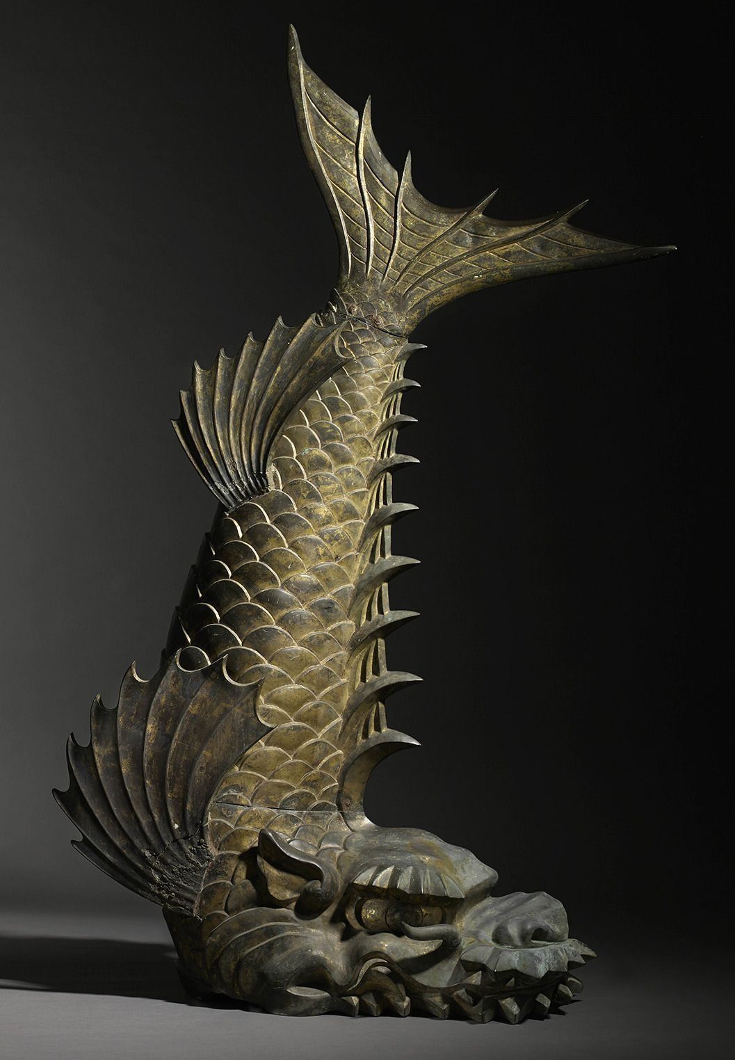 A statue of a fish with a long tail is sitting on a table.