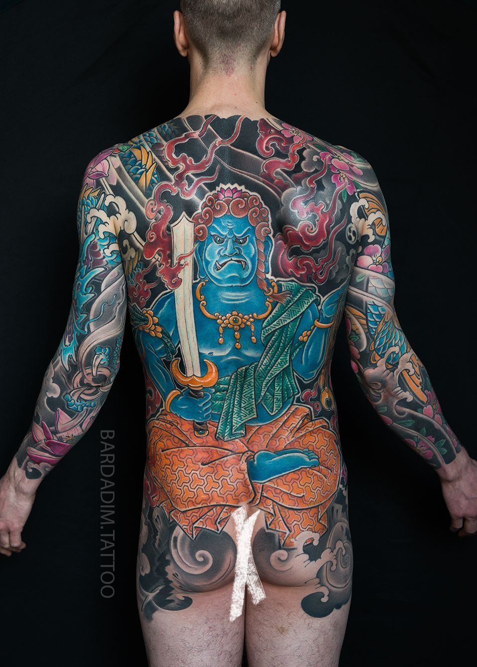 Back view of a person with a full-body Japanese-style tattoo featuring a blue deity holding a sword done at Bardadim Tattoo.
