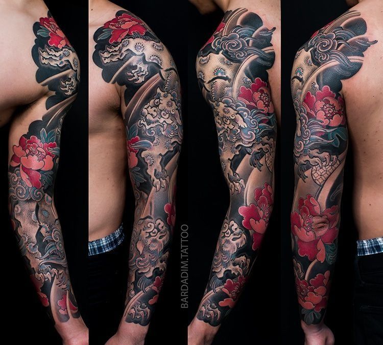 A man has a full sleeve tattoo on his arm and shoulder.