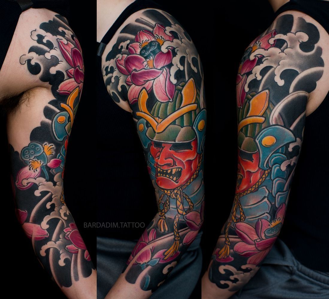 Japanese-style full-sleeve tattoo: Oni mask and lotus flowers against a wave background.