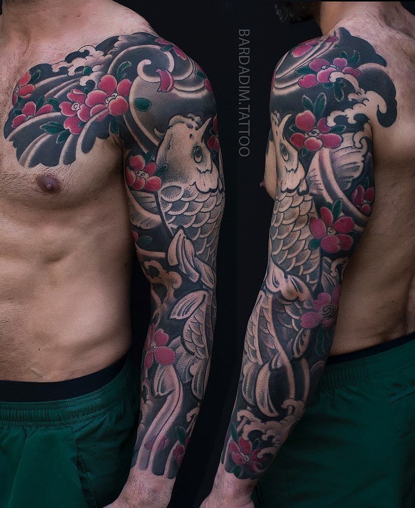 A man has a full sleeve tattoo of a fish and flowers.
