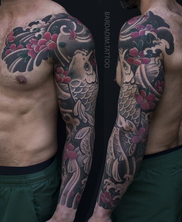 A man has a full sleeve tattoo of a fish and flowers