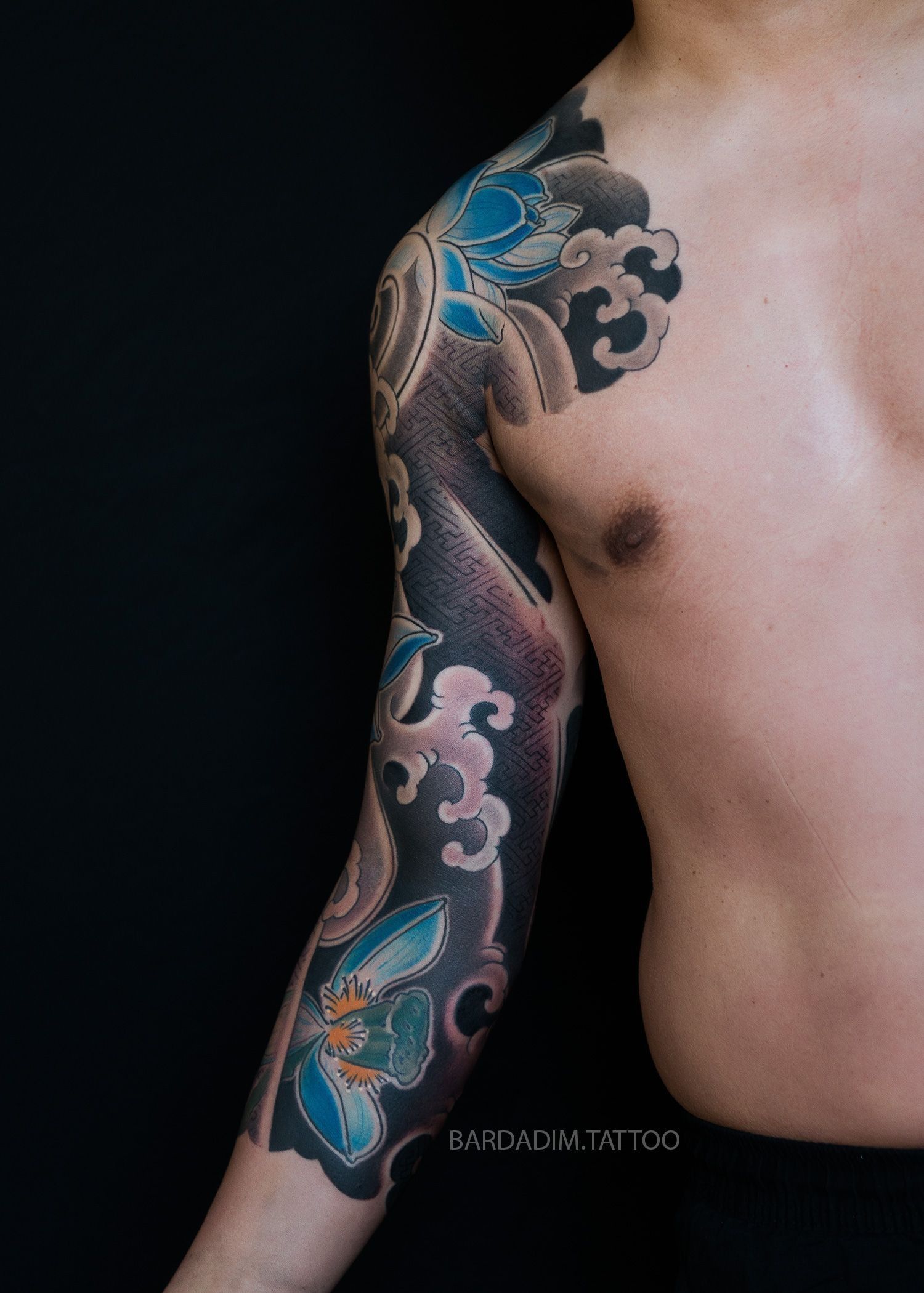 A man has a tattoo on his arm and shoulder.