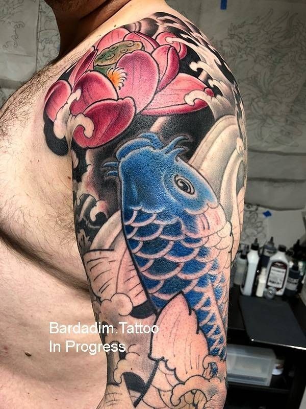 A man has a tattoo of a fish and a flower on his arm.