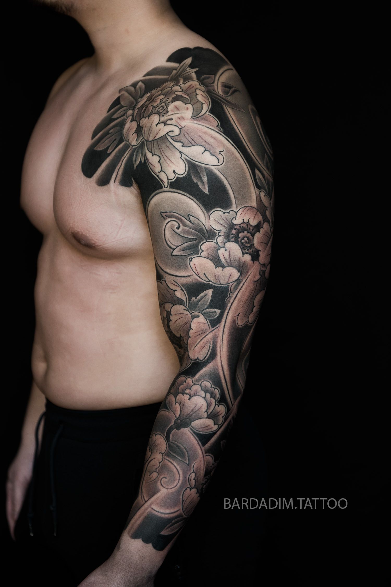 Front angle of Bardadim’s white peony sleeve tattoo emphasizing bold contrasts and smooth gendai-style shading.