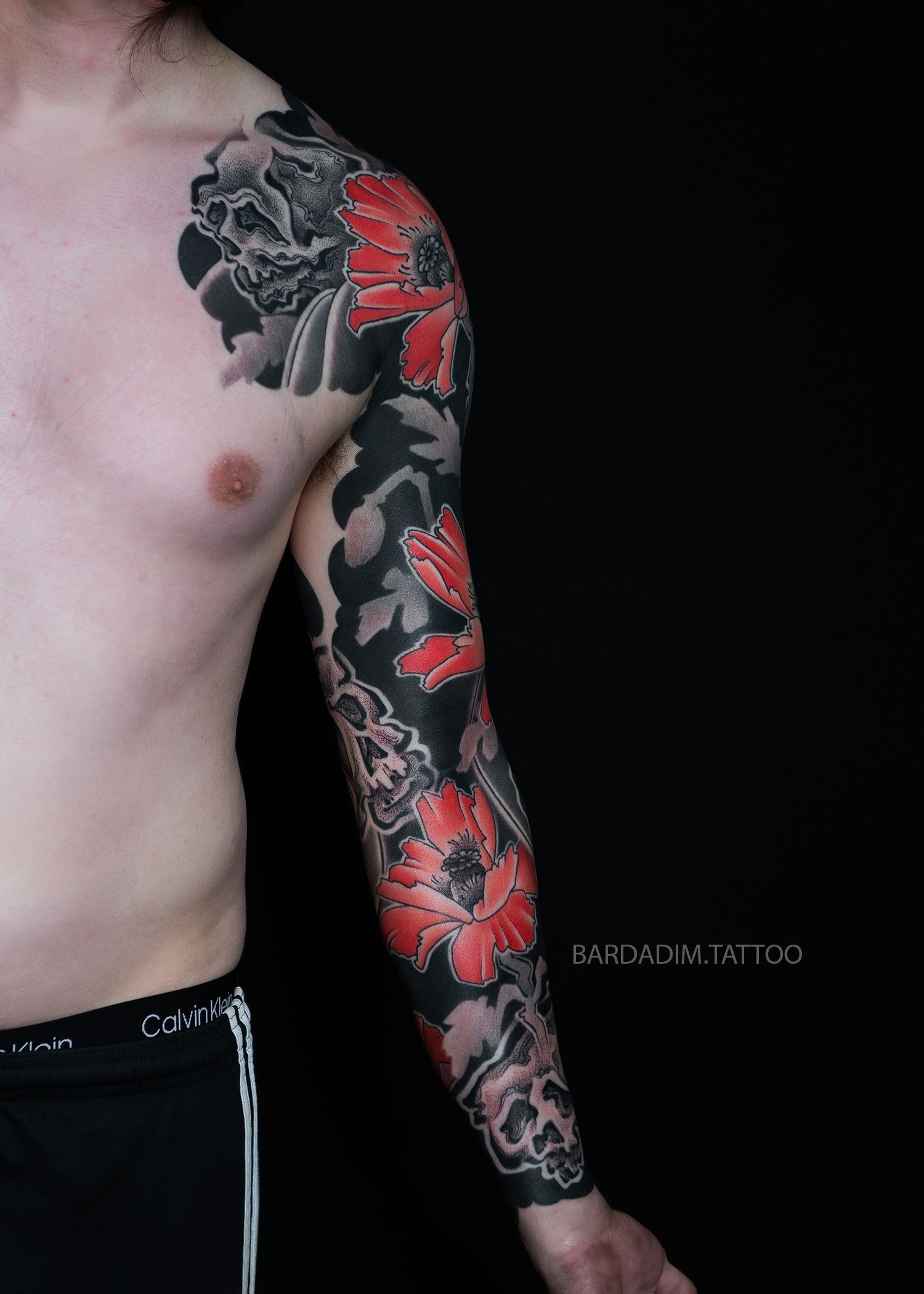 A man with a black and red tattoo on his arm.