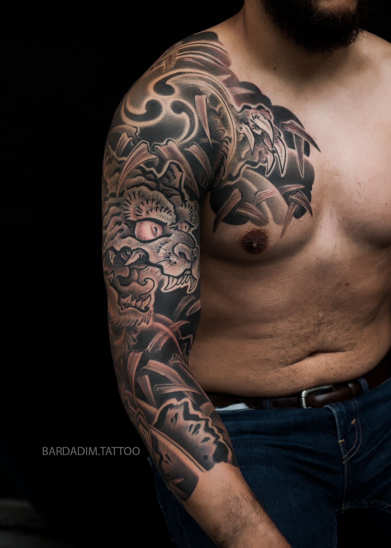 A shirtless man with a tattoo on his arm and chest.