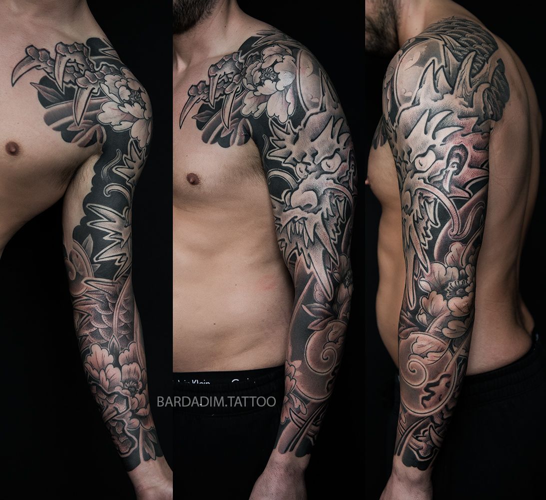 Man with a detailed black and grey tattoo sleeve covering his arm. Tattoo features clouds, flowers and abstract imagery.