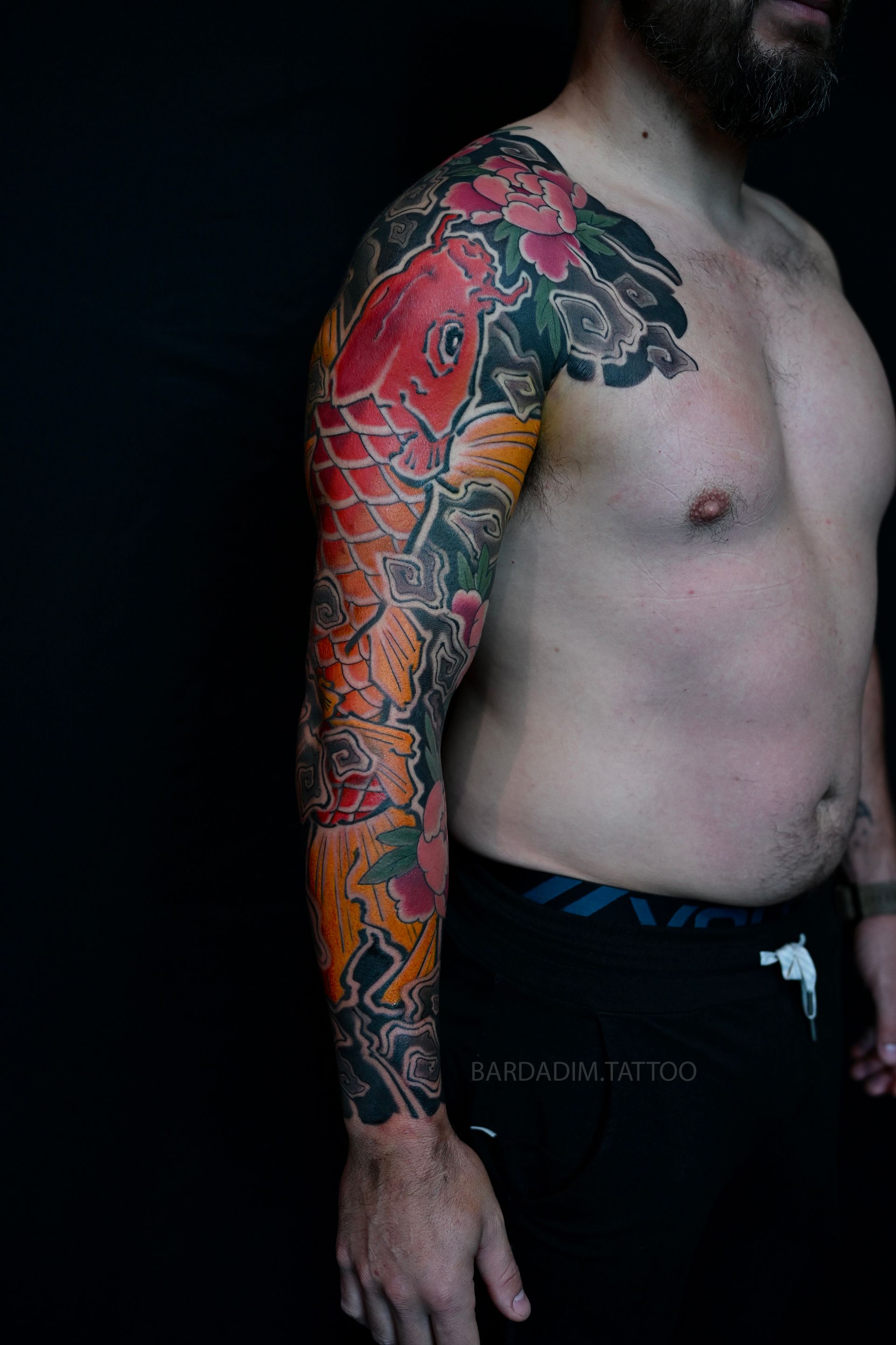 Orange koi head and peony tattoo on upper arm