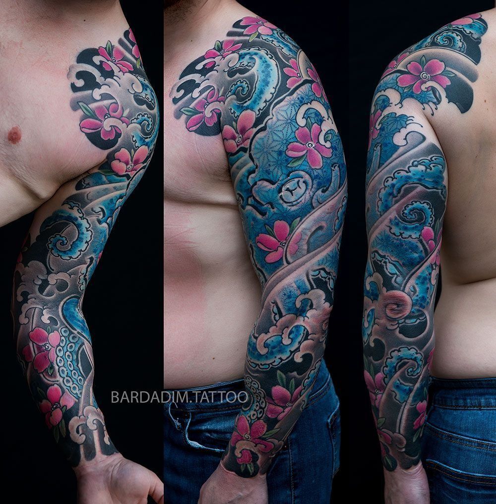 A man has a full sleeve tattoo of flowers and waves