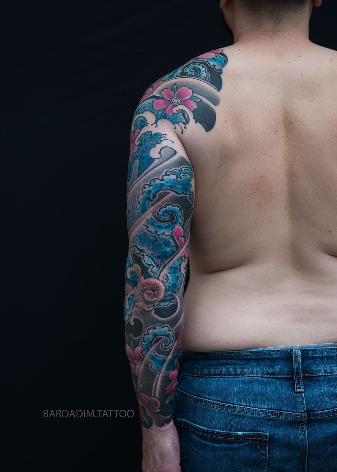 A man with a full sleeve tattoo on his arm and back.