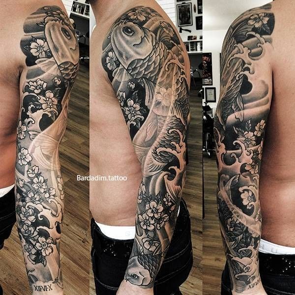 A man has a full sleeve tattoo of a fish and flowers