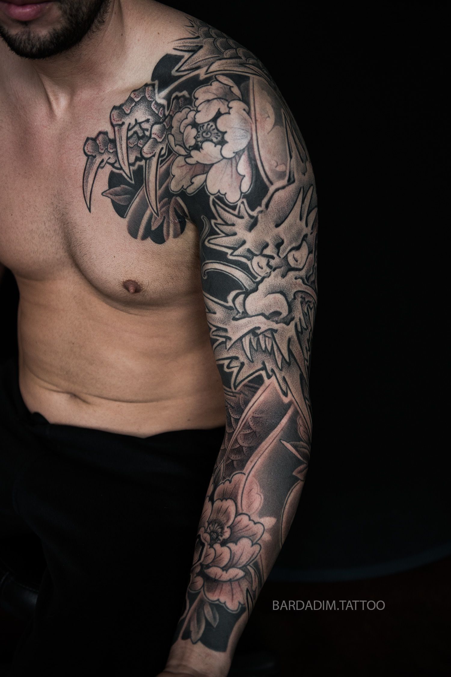 A man without a shirt has a full sleeve tattoo on his arm.