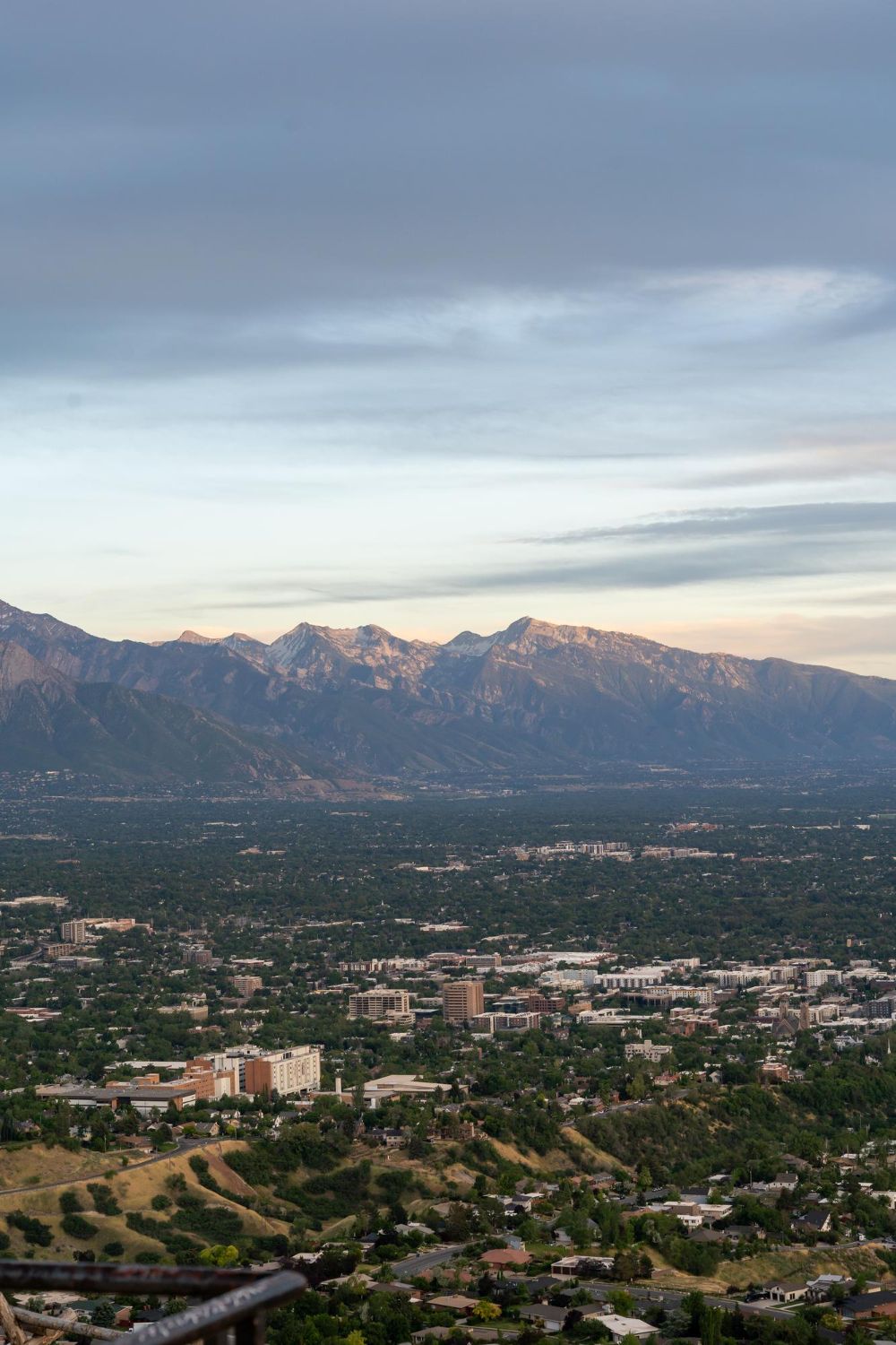 Cityscape with mountains in the background under a cloudy sky at dusk.