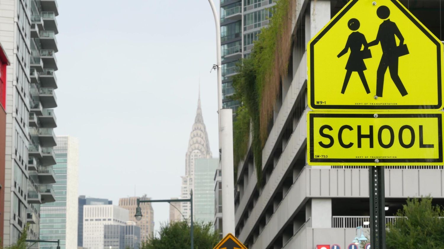 School zone sign with a silhouette of children walking, city background.