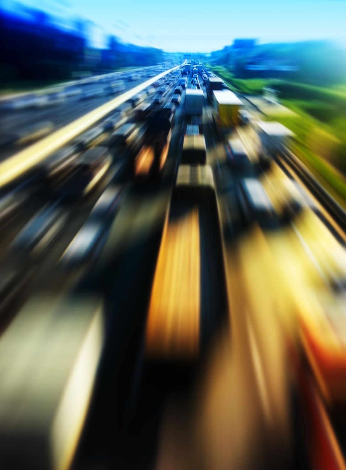 Traffic jam on a highway, motion blur effect; cars and trucks, bright sky.