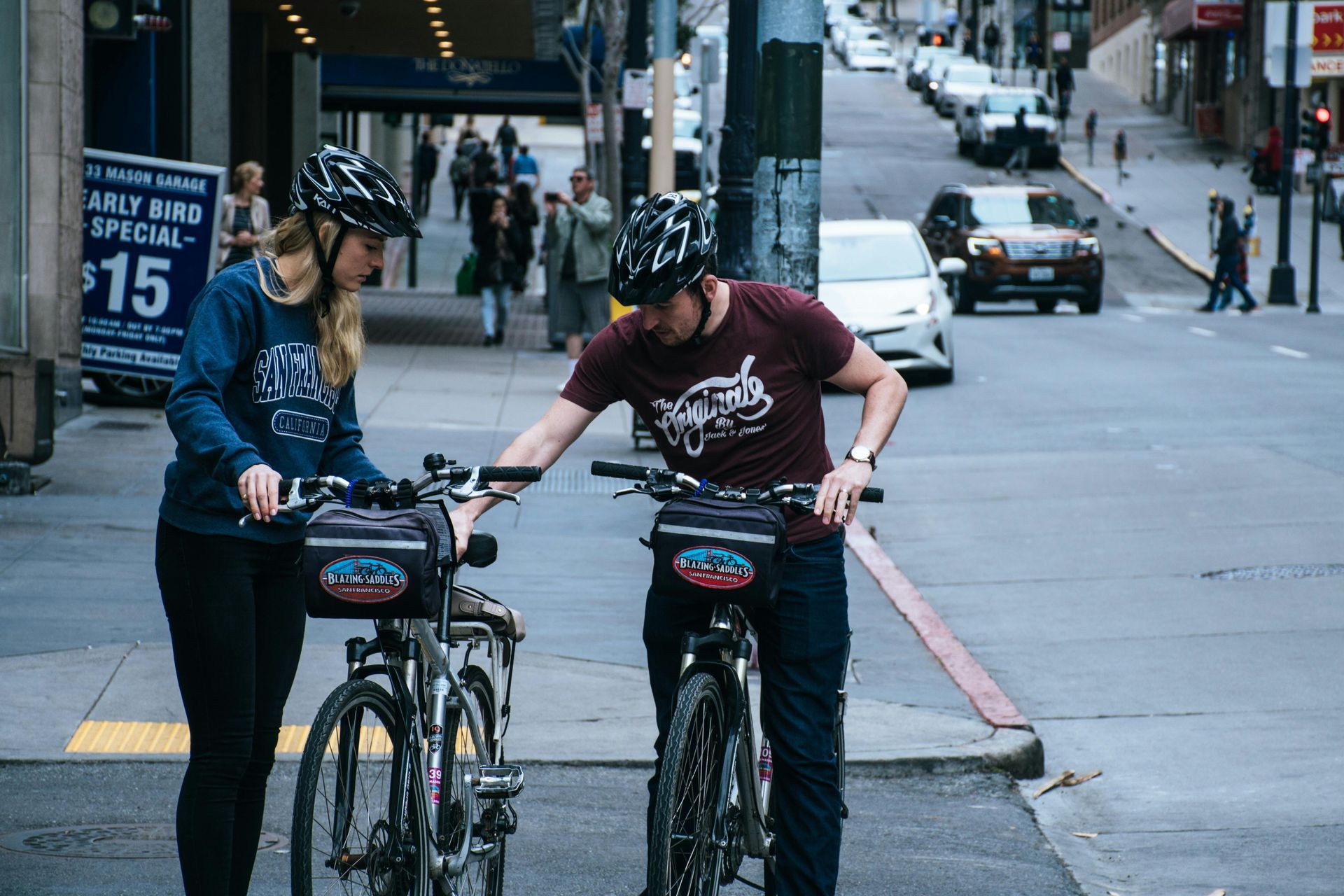 Two people wearing helmets beside bikes on a city street.