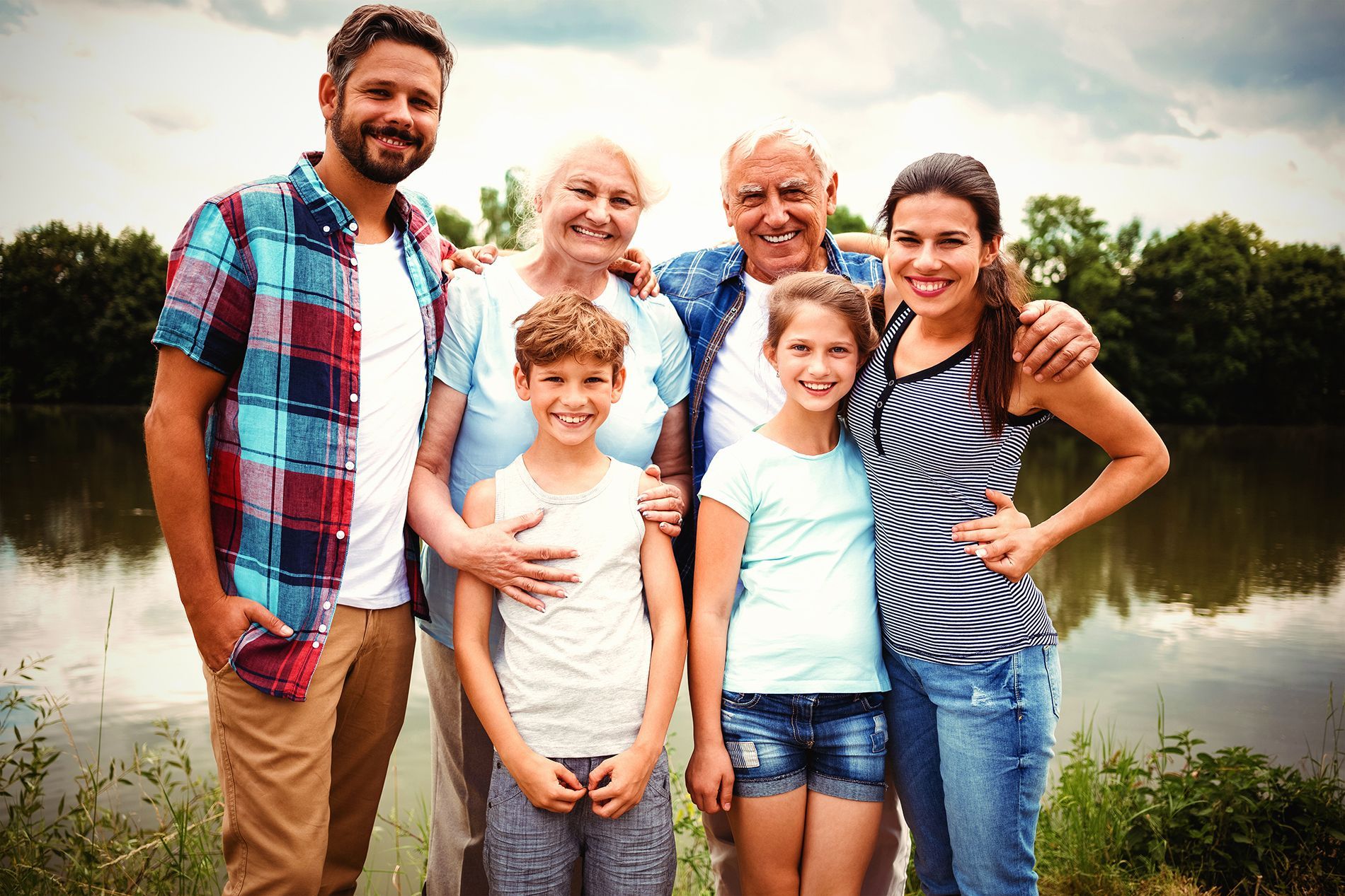 Family of seven posing near a lake, smiling.
