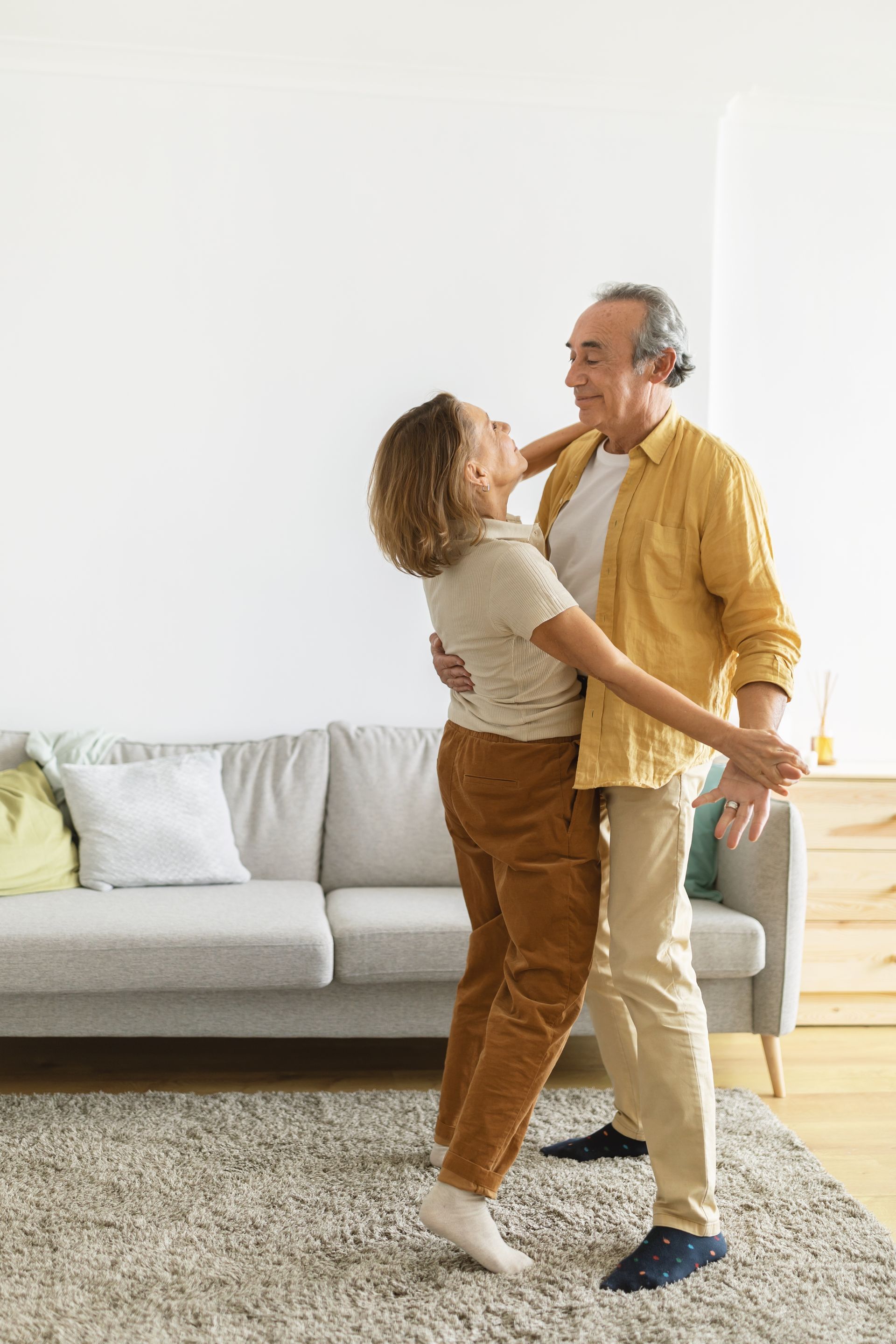 A man and a woman are dancing in a living room.