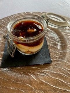 Dessert in barattolo con copertura al caramello su un piatto testurizzato.