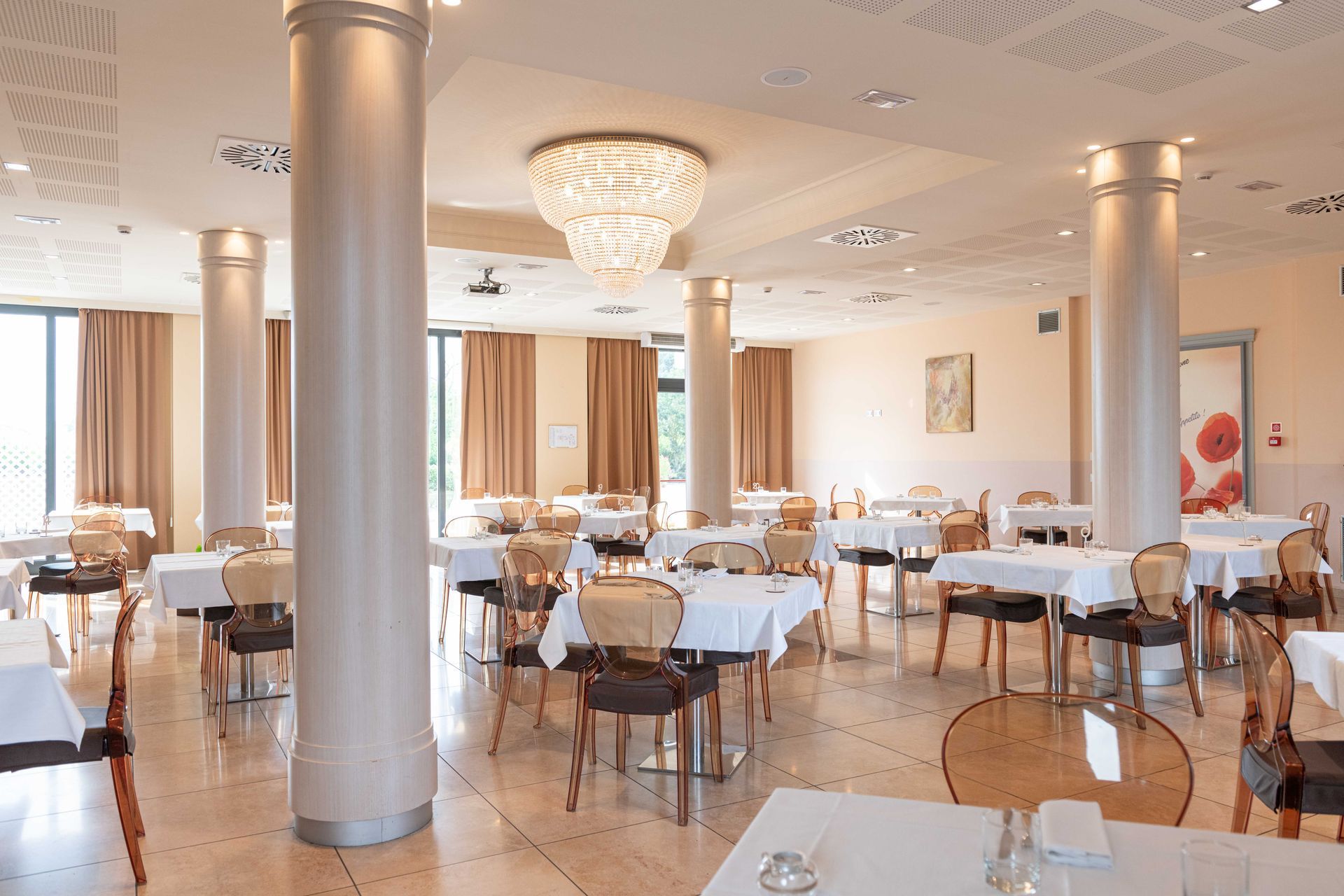 Elegante interno del ristorante con tavoli, sedie, colonne e un lampadario.