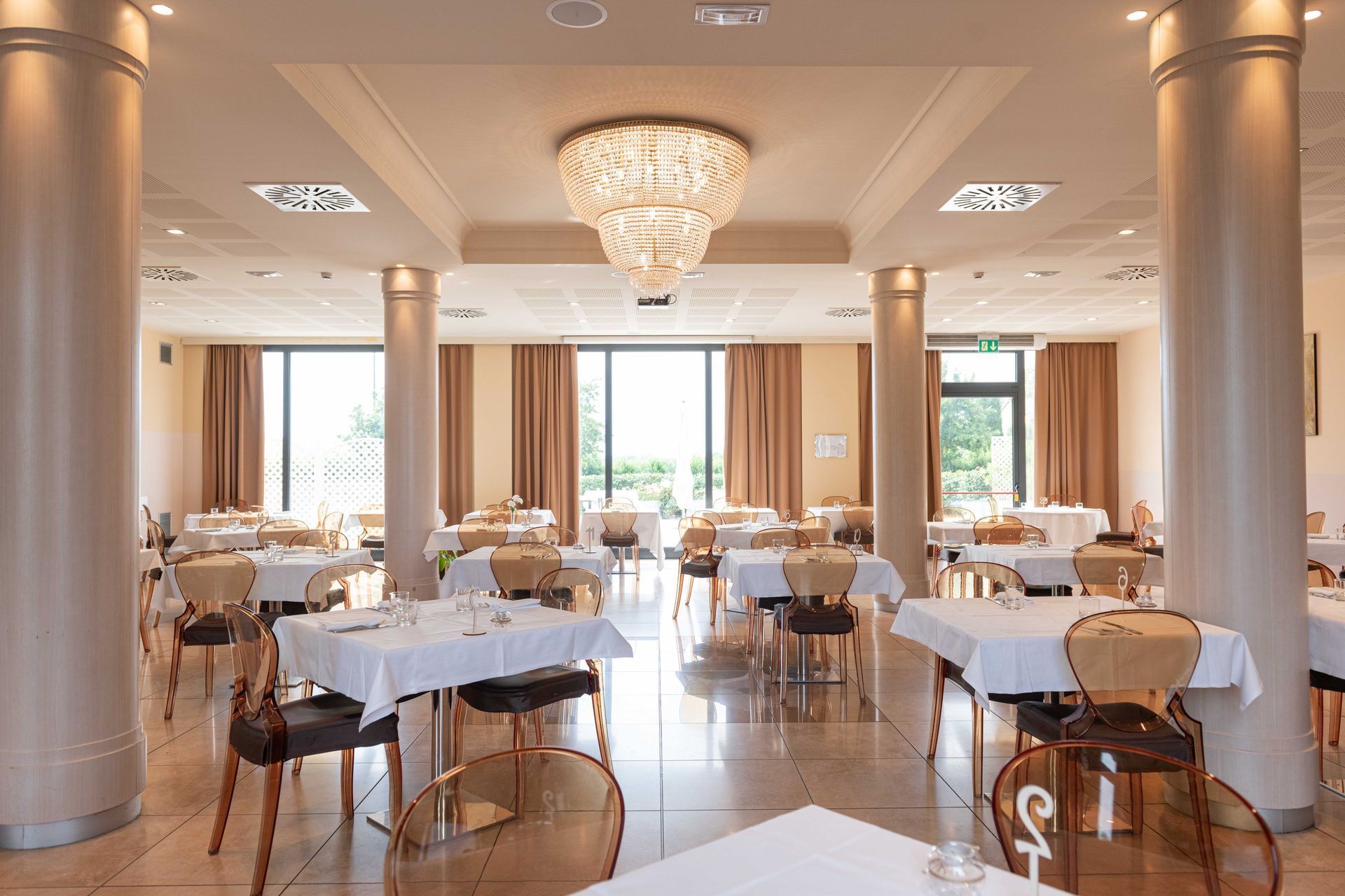 Elegante interno del ristorante con tavoli, sedie, colonne e un lampadario.