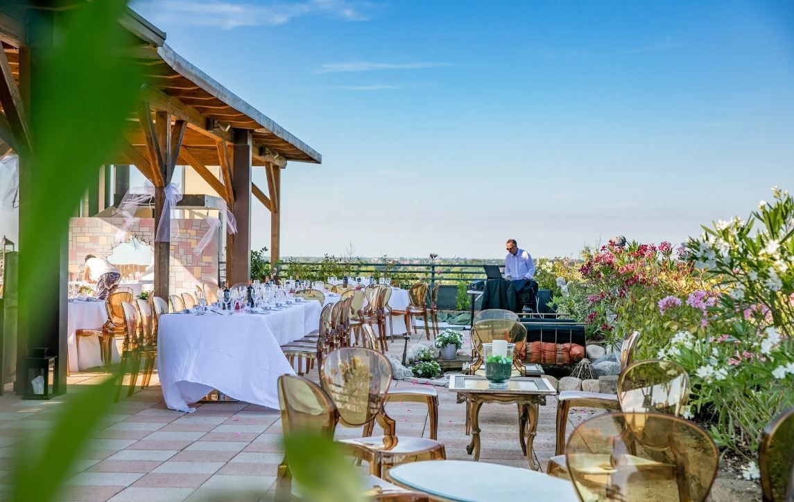Ricevimento di nozze all'aperto con tavoli, sedie e un musicista su un patio con vista sul paesaggio.